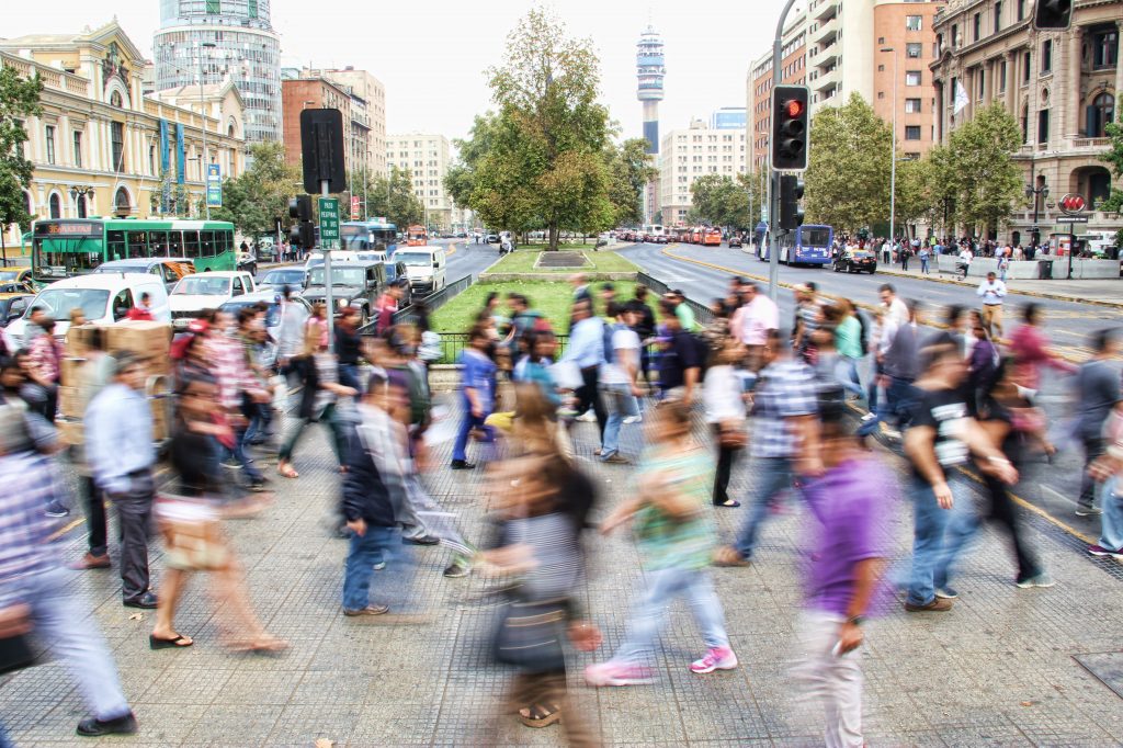 blurry people walking through an intersection during the day in a big city